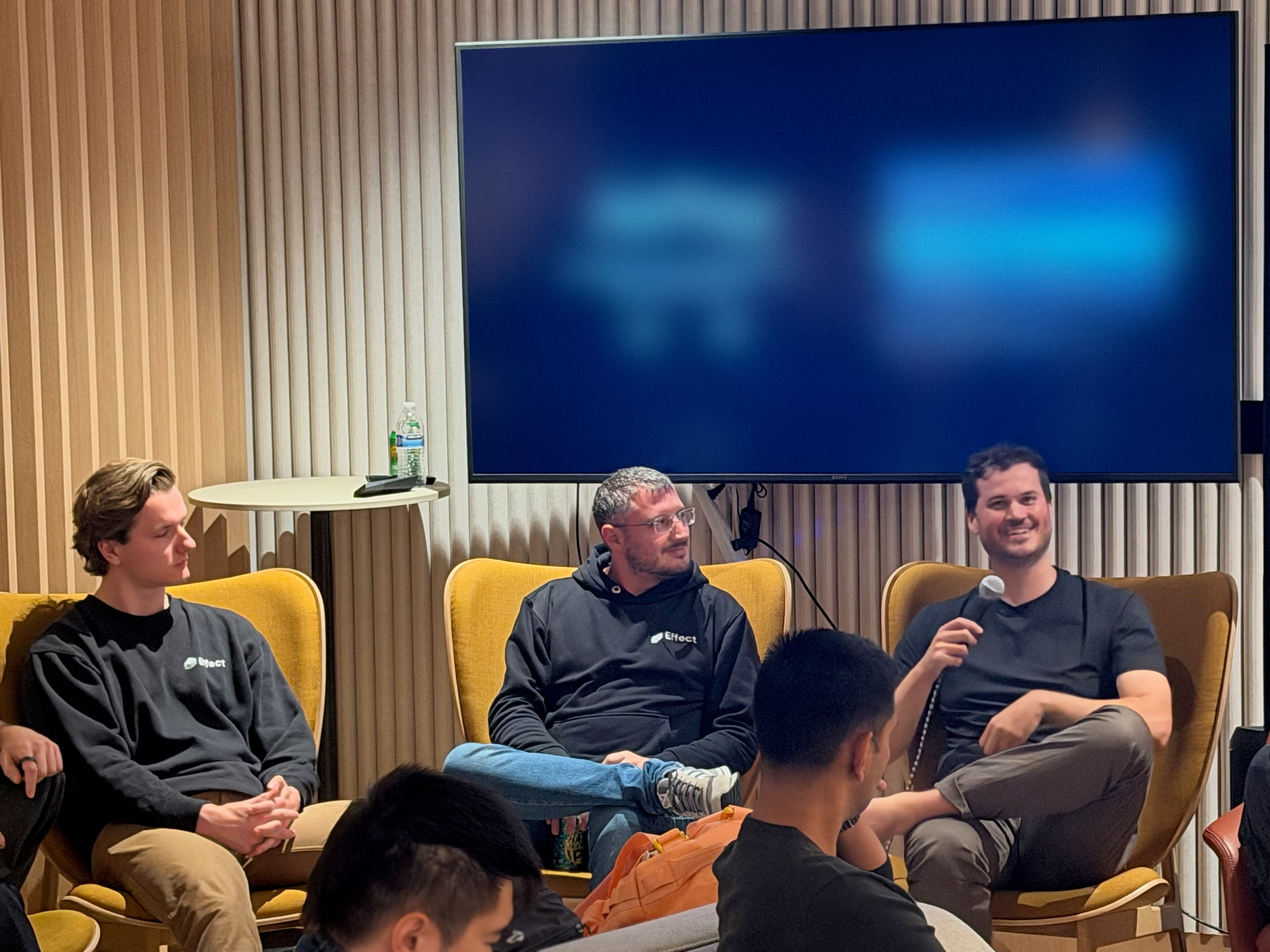 Three panelists in armchairs taking a question at CodeRabbit, the audience in the foreground