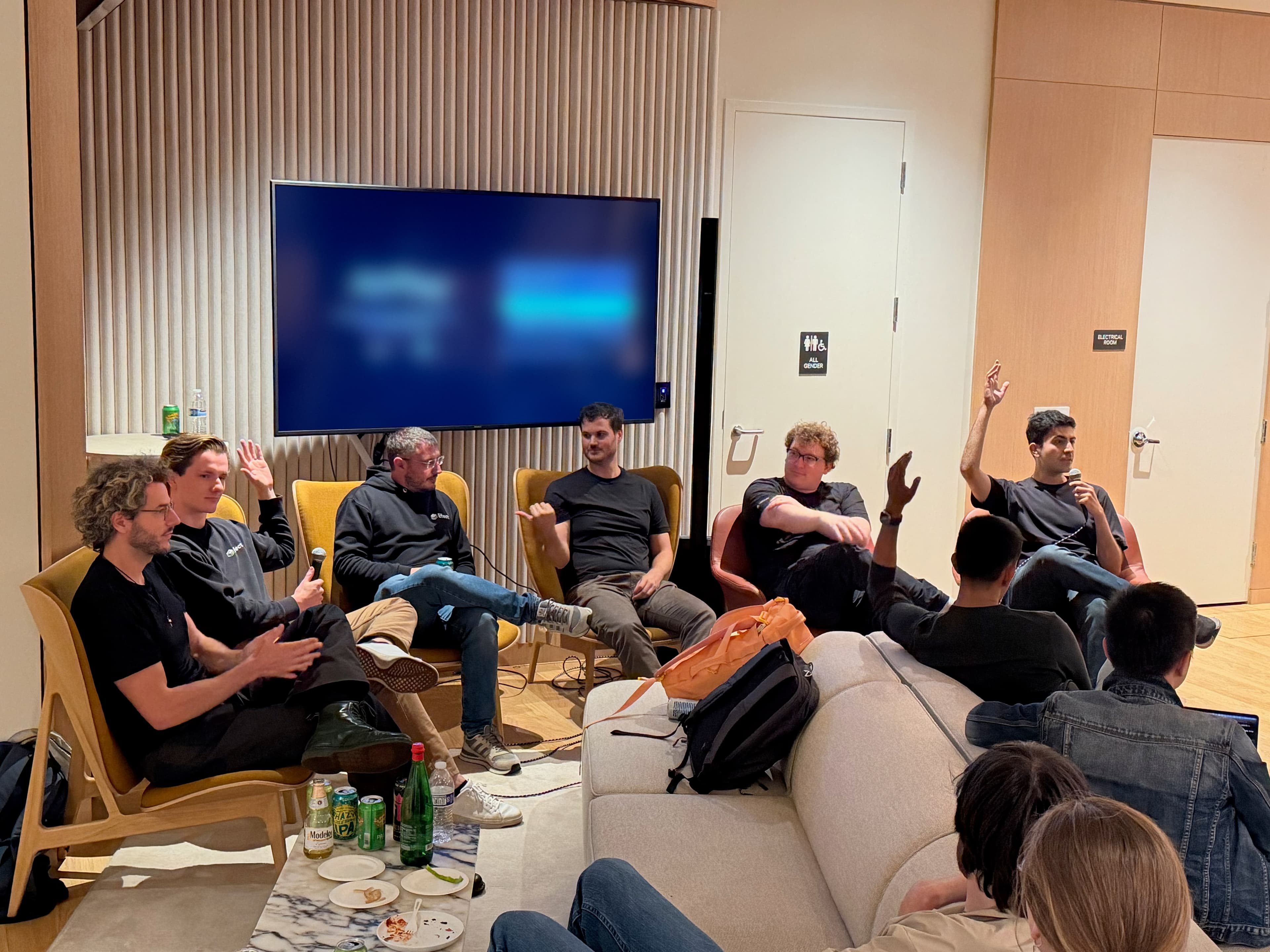 The panel in armchairs at CodeRabbit, with hands raised on stage and in the audience